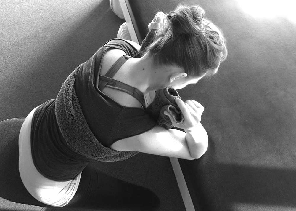 Sydney demonstrates resting your elbows on a flat surface during rib cage breathing to help you relax your shoulders.