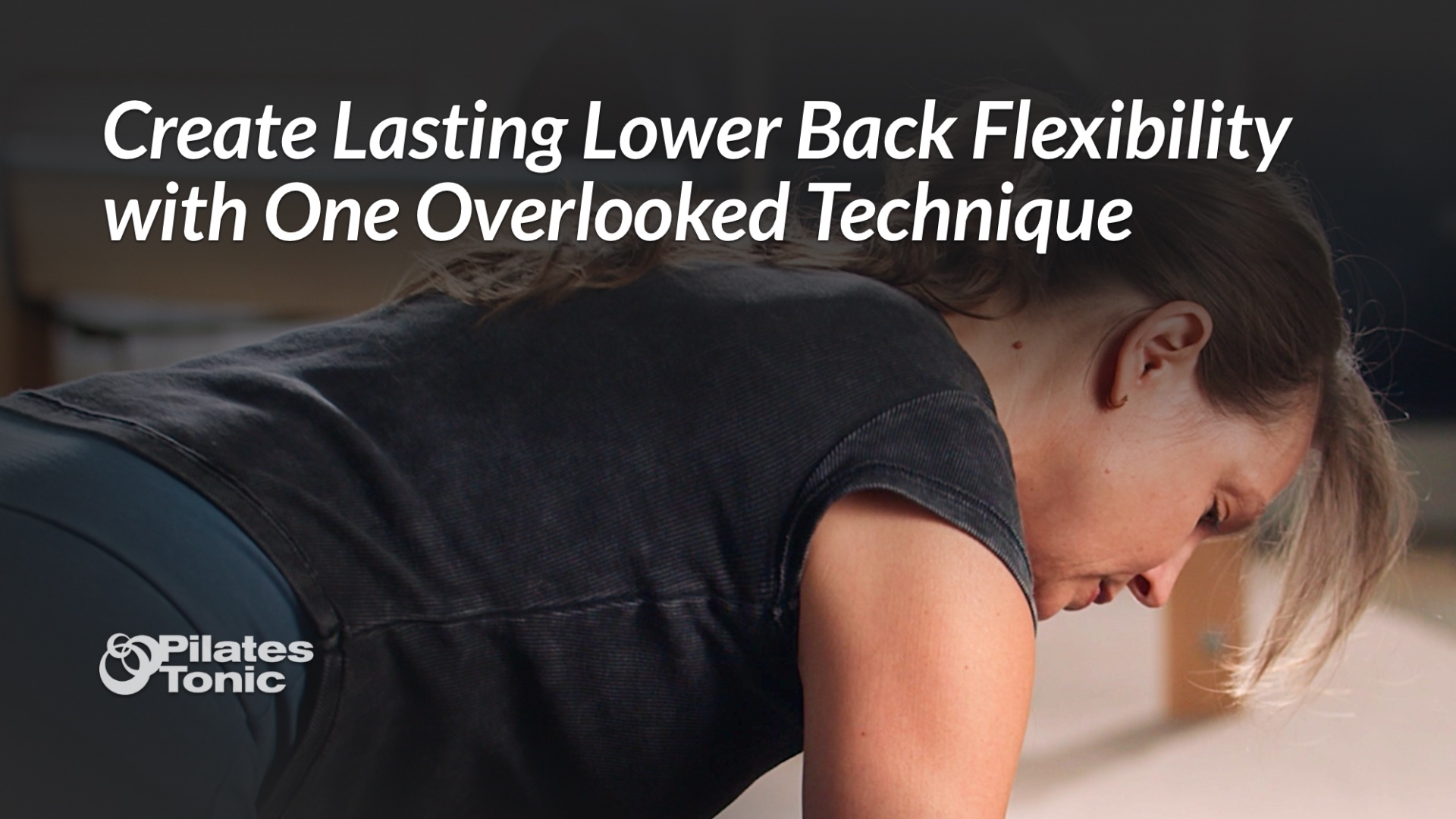 Woman in black shirt performing spinal flexion exercise on Pilates equipment to improve lower back flexibility.